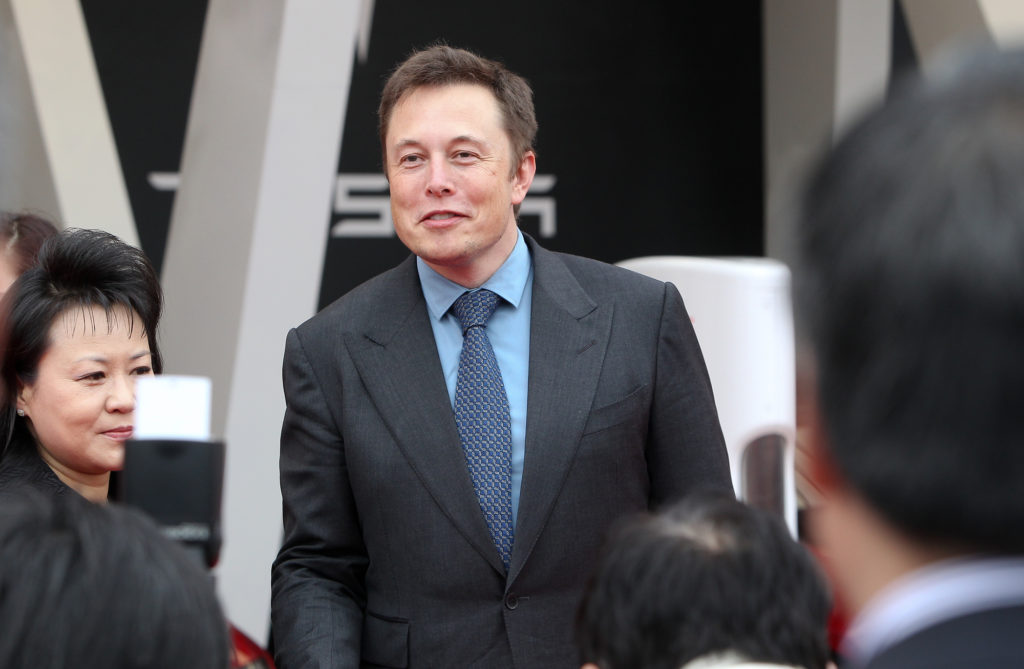 Elon Musk wearing a suit with a blue shirt and blue tie. Photo via ChinaImages