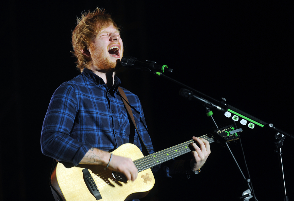 Ed Sheeran performing on stage with an acoustic guitar