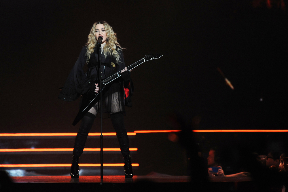 Madonna on stage holding a guitar during a performance in Prague in 2015.