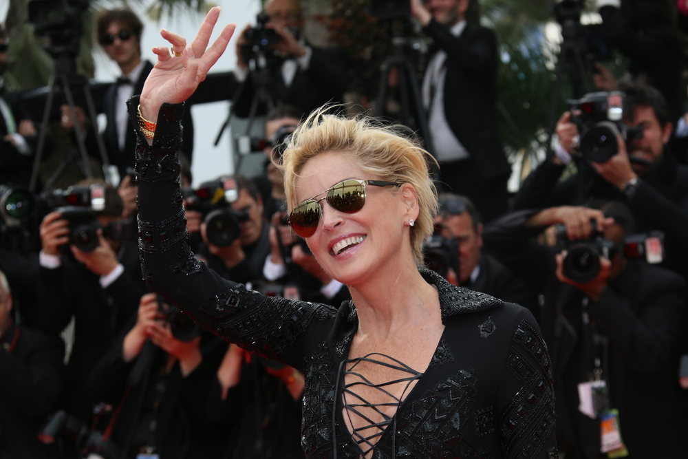 Sharon Stone wearing aviator sunglasses and waving during an event