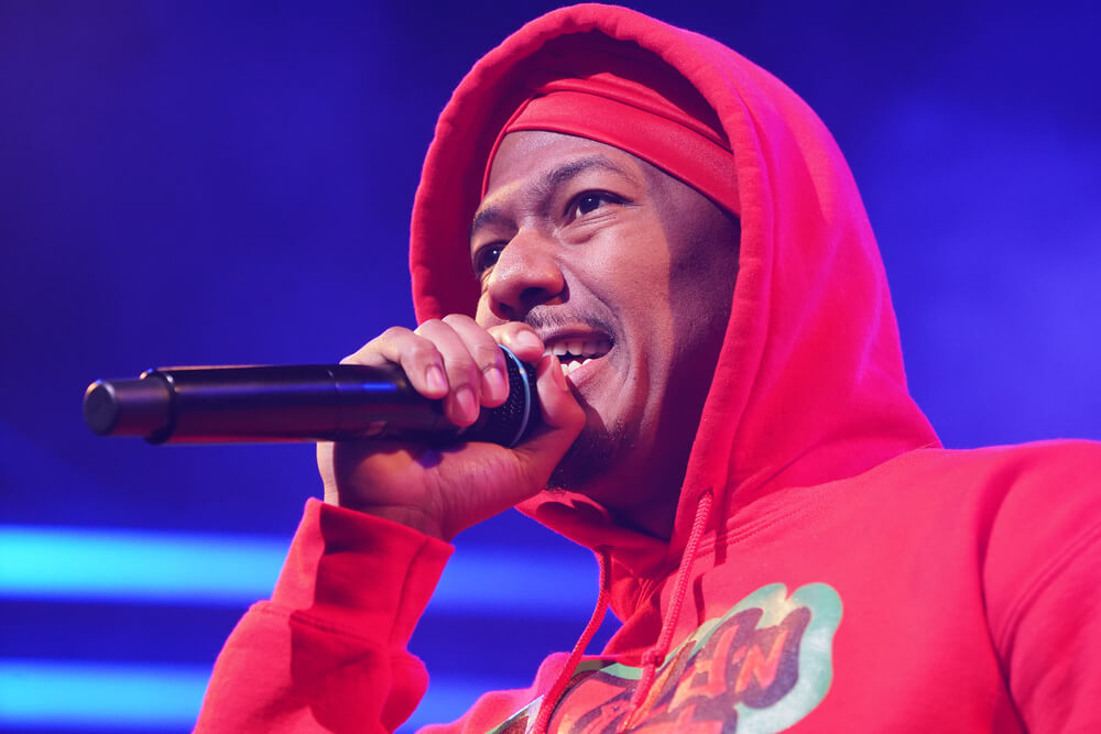 Rapper Nick Cannon wears red sweatshirt with hood up while rapping at MTV awards show